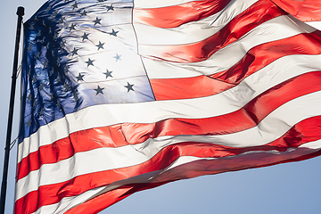 Image showing Backlit American Flag Waving In Wind Against a Deep Blue Sky