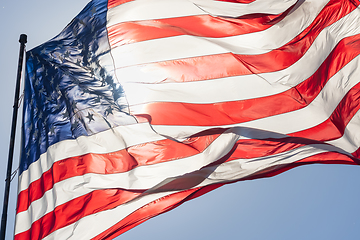 Image showing Backlit American Flag Waving In Wind Against a Deep Blue Sky