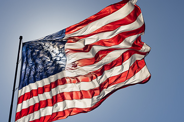 Image showing Backlit American Flag Waving In Wind Against a Deep Blue Sky