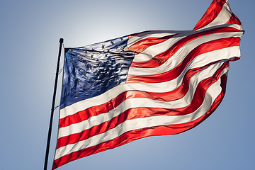 Image showing Backlit American Flag Waving In Wind Against a Deep Blue Sky