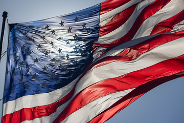 Image showing Backlit American Flag Waving In Wind Against a Deep Blue Sky