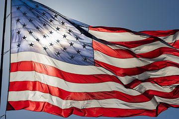 Image showing Backlit American Flag Waving In Wind Against a Deep Blue Sky