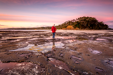 Image showing Woman watching the sunrise from the outer rocky reef