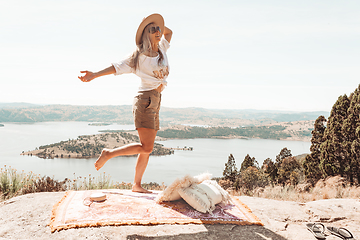 Image showing Woman dancing high on a rocky outcrop with views over waterways