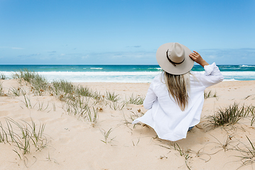 Image showing Woman sits on a clean sandy beach in Australia