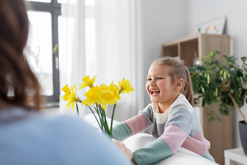 Image showing happy daughter giving daffodil flowers to mother