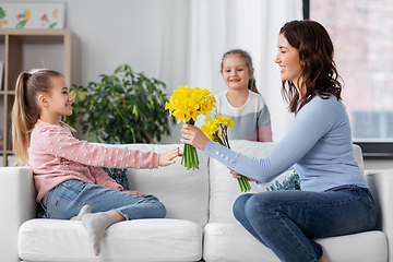 Image showing daughters giving daffodil flowers to happy mother