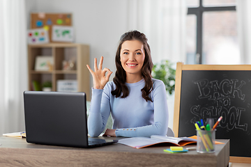 Image showing teacher with laptop and notebook working from home