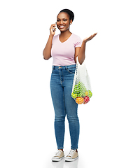 Image showing woman with food in net bag calling on smartphone