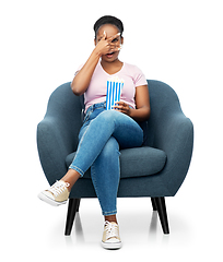 Image showing scared woman eating popcorn sitting in armchair