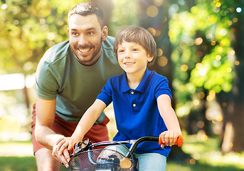 Image showing father teaching little son to ride bicycle at park