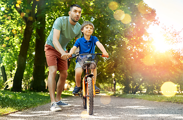 Image showing father teaching little son to ride bicycle at park