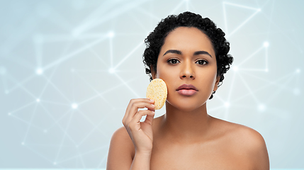 Image showing young woman cleaning face with exfoliating sponge