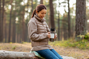 Image showing asian woman with thermos drinking tea in forest