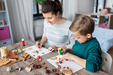 Image showing mother and son making pictures of autumn leaves