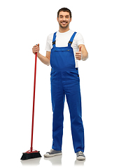 Image showing male cleaner in overall cleaning floor with broom