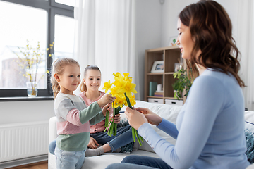 Image showing daughters giving daffodil flowers to happy mother