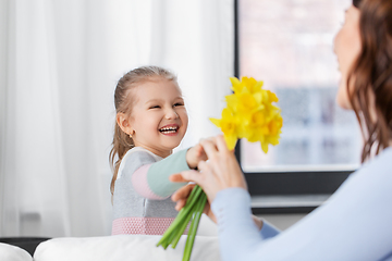 Image showing happy daughter giving daffodil flowers to mother