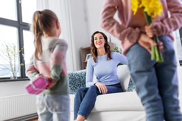 Image showing daughters giving flowers and gift to happy mother