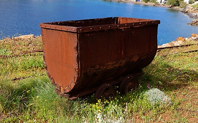 Image showing Old rusty coal tub or trolley on tracks, on the sea cliff in Megalo Livadi village, Serifos island, Greece