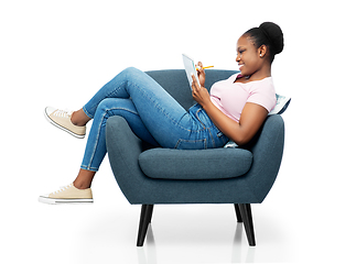 Image showing happy young woman in armchair writing to notebook