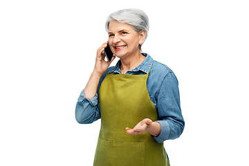 Image showing senior woman in garden apron calling on smartphone