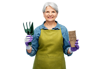 Image showing old woman in apron with pots and garden tools