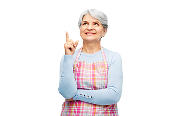 Image showing smiling senior woman in apron pointing finger up