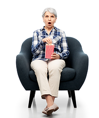 Image showing senior woman eating popcorn sitting in armchair