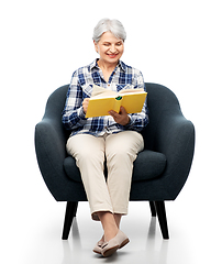 Image showing senior woman reading book sitting in armchair