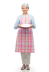 Image showing smiling senior woman in apron with empty plate