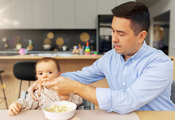 Image showing middle-aged father feeding baby daughter at home