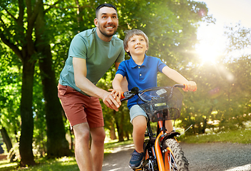 Image showing father teaching little son to ride bicycle at park