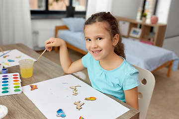 Image showing little girl painting wooden items at home