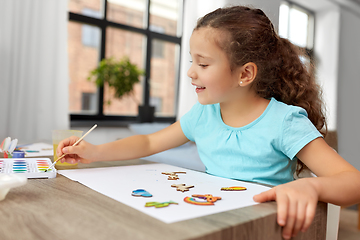 Image showing little girl painting wooden items at home