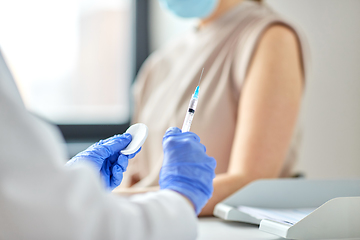 Image showing female doctor with syringe vaccinating patient