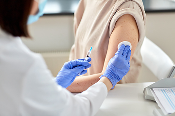 Image showing female doctor with syringe vaccinating patient