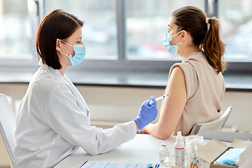 Image showing female doctor with syringe vaccinating patient