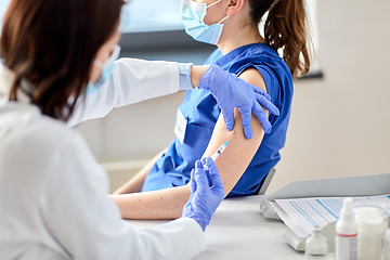 Image showing doctor with syringe vaccinating medical worker