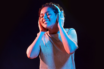 Image showing woman in headphones listening to music and dancing