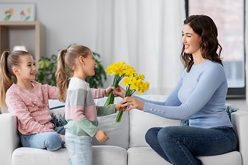 Image showing daughters giving daffodil flowers to happy mother