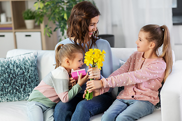 Image showing daughters giving flowers and gift to happy mother