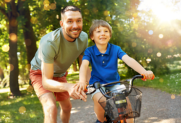 Image showing father teaching little son to ride bicycle at park