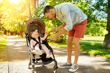 Image showing father with child sitting in stroller at park