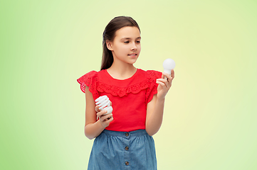 Image showing smiling girl comparing different light bulbs