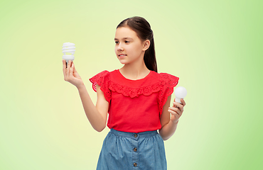 Image showing smiling girl comparing different light bulbs