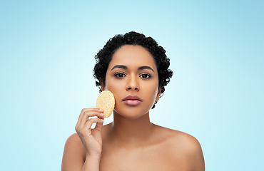 Image showing young woman cleaning face with exfoliating sponge