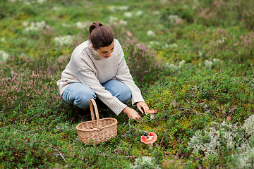 Image showing young woman picking mushrooms in autumn forest