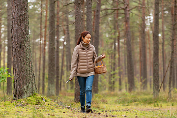 Image showing young woman picking mushrooms in autumn forest