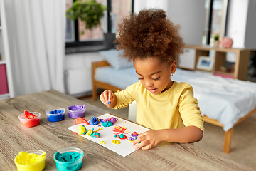 Image showing little girl with modeling clay playing at home